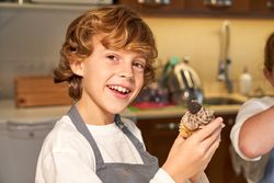 Smiling boy with homemade cupcake in paper baking tin