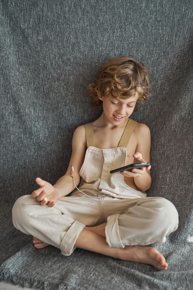 Cheerful boy charging himself from smartphone