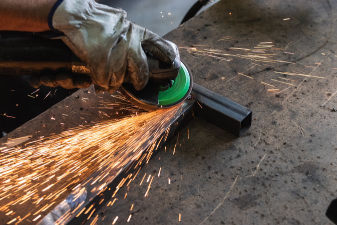 Male worker using electric grinder in workshop