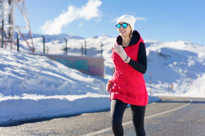 Woman in wintry gear jogging on road in the mountains on cold day