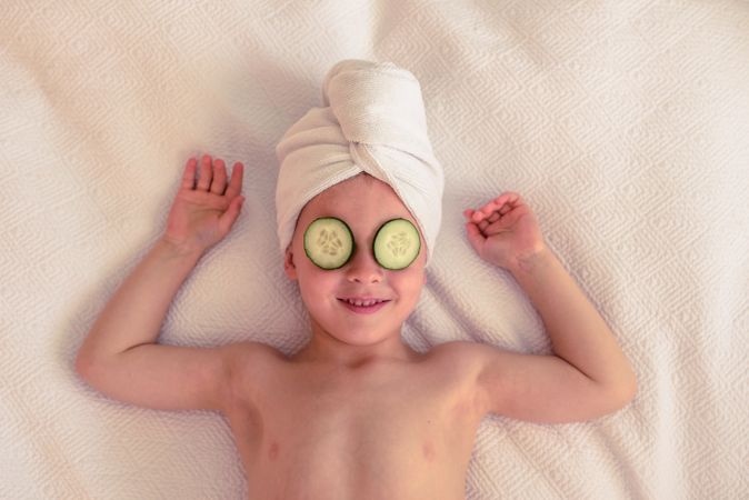 Delighted boy with cucumber on eyes