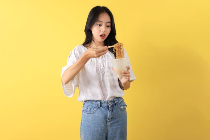 Young Indonesian Teenager Eating Instant Noodles using Chopstick
