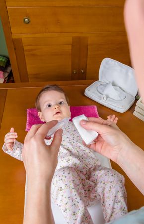 Closeup of mother hands pouring physiological serum in a cotton to clean the eyes of baby