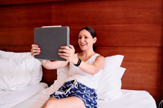 a young woman lying on a hotel bed using a tablet