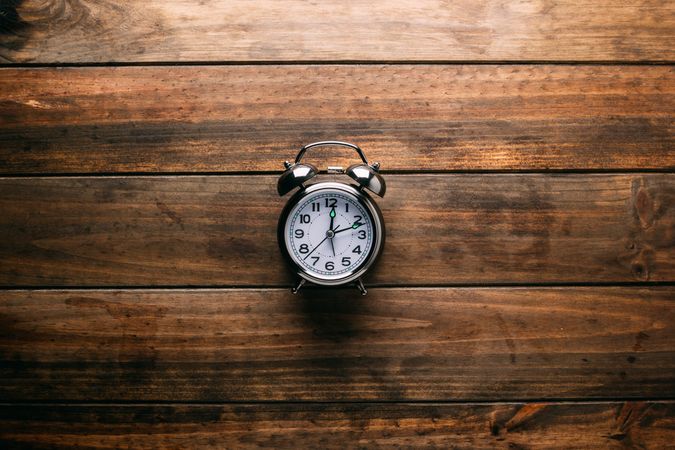 Mechanical alarm clock lying on wooden tabletop