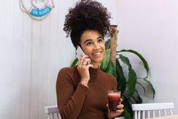 Content Black woman speaking on mobile phone in cafe