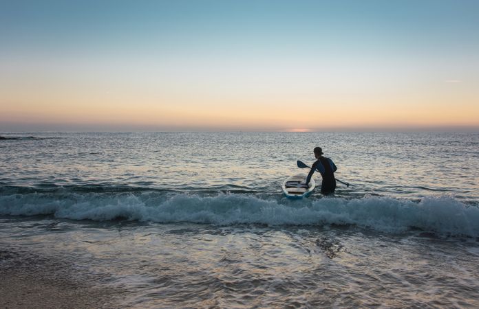 Man practicing paddle surfing with neoprene in a sunrise