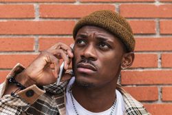 Man speaking on smartphone near brick wall
