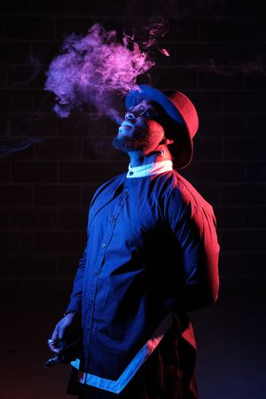 Black male blowing smoke in darkness