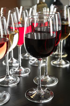Bottles and glasses with wine on dark table, close up
