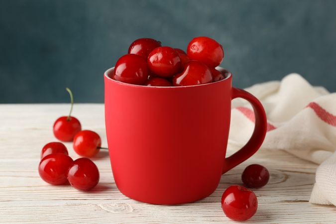 Towel and cup with cherry on wooden background