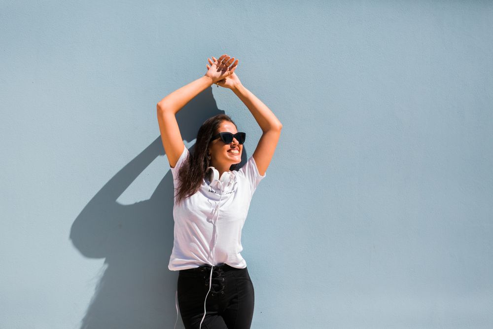 Cheerful casual woman in sunglasses standing on city street
