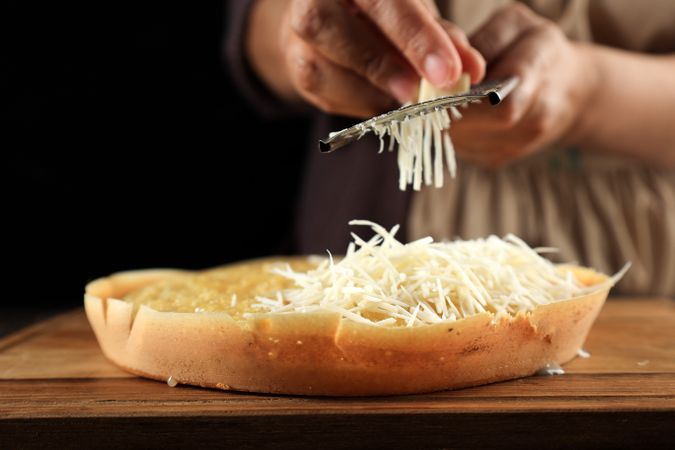 Woman Hand Grating Cheese to the Martabak Manis Terang Bulan at Wooden Table