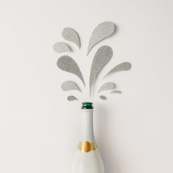 Champagne bottle with silver glittering splashes on light background
