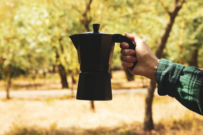 Female hand in shirt hold coffee maker outdoor