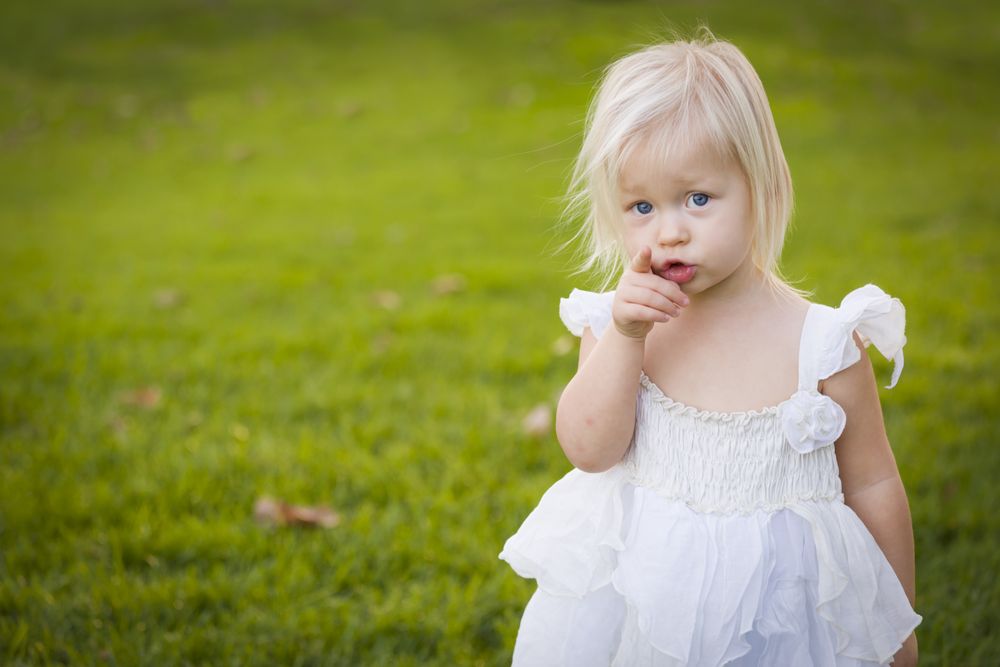 Adorable Little Girl Wearing Dress In A Grass Field