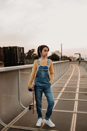 Girl with skateboard on walkway