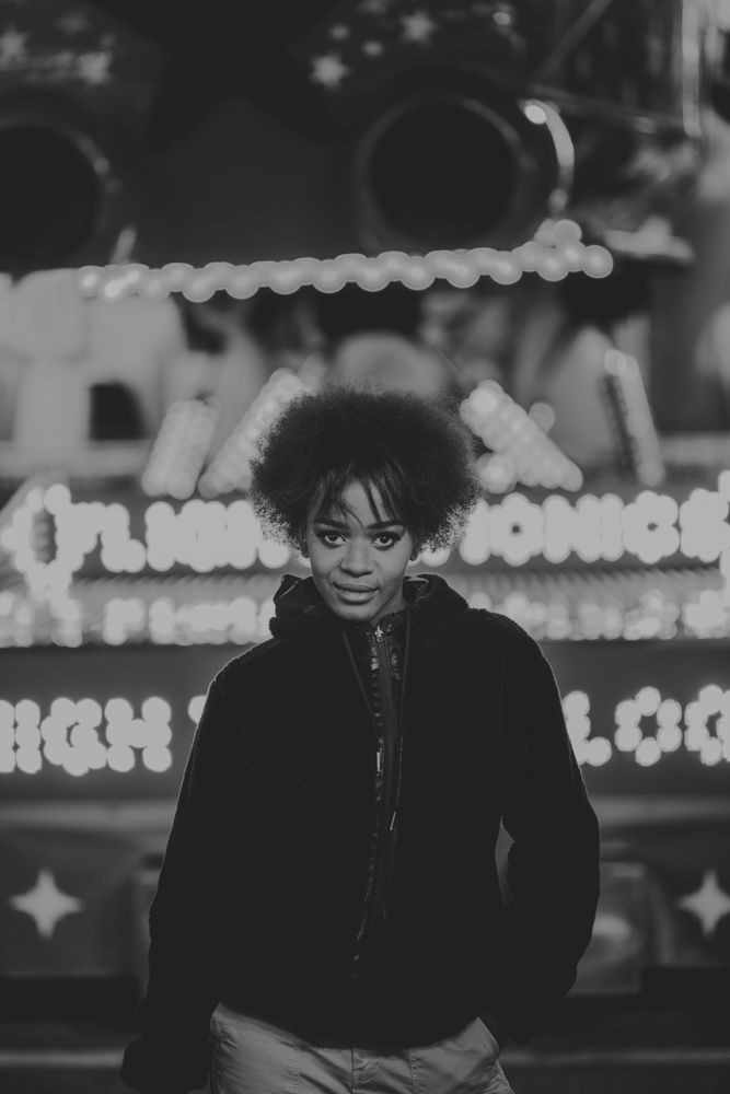Black female standing near attraction in amusement park