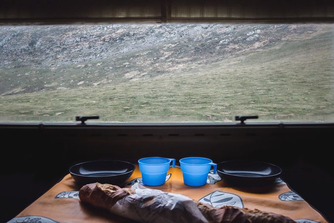Bread and dishware near window of countryside dwelling
