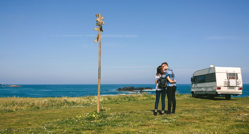 Couple kissing near the coast with a camper