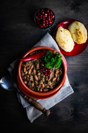 Top view of Georgian bean dish served with rolls and pomegranates 