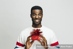 Excited Black man holding up a present wrapped in red with both hands 0gdne5