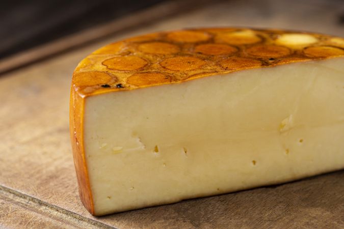 close up of cheese round half on bread board