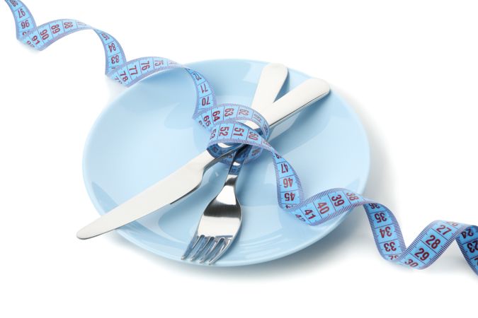 Cutlery with measuring tape isolated on blank background