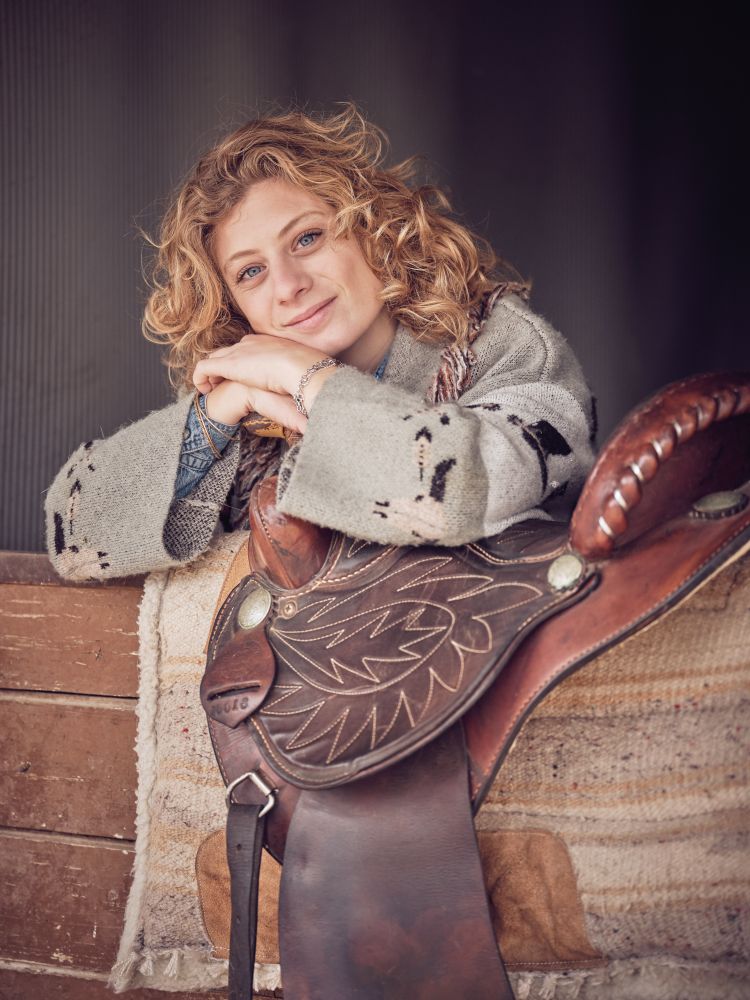Delightful person with saddle in wooden stable