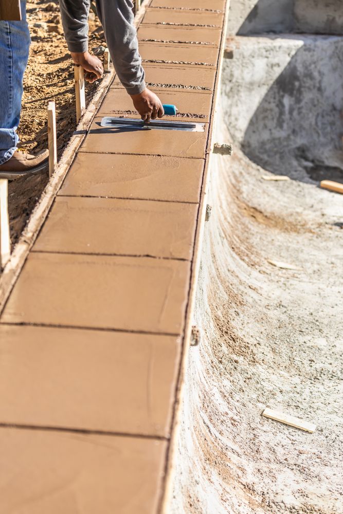 Construction Worker Using Trowel On Wet Cement Forming Coping Around New Pool