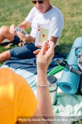 Back of woman holding up ace of diamonds card on picnic 4mJyvb
