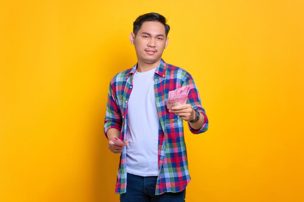 Serious Asian man holding money in studio shoot