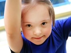 Close up portrait of little girl in blue shirt looking at camera