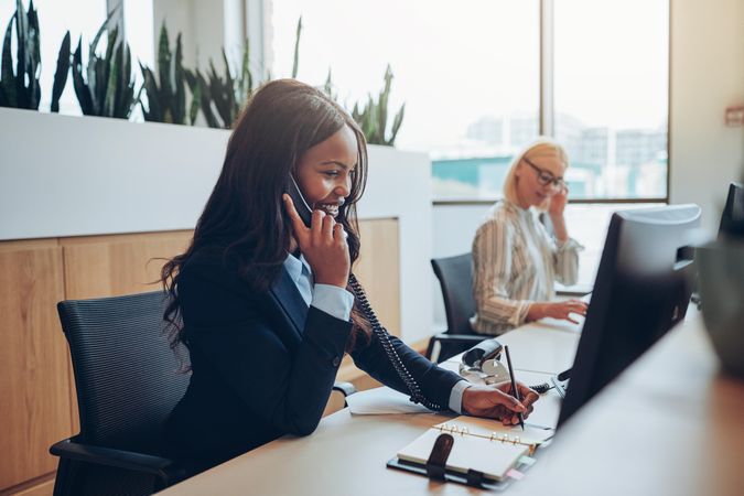 Women at the front desk smiling while taking notes