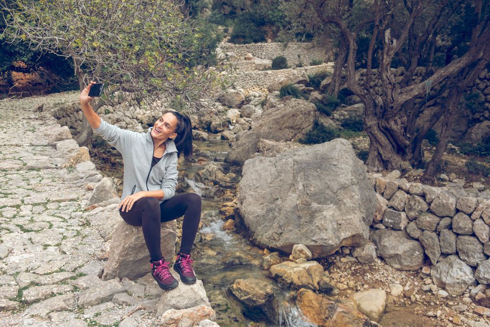 Cheerful female traveler taking selfie on smartphone