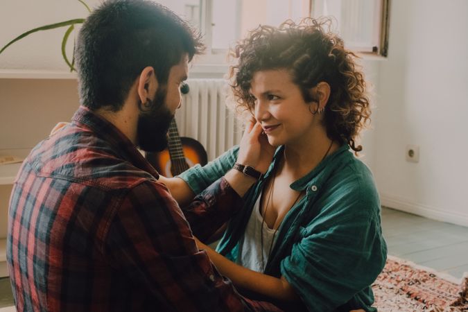 Loving couple embracing while sitting on apartment floor