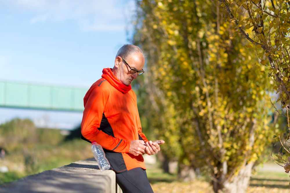 Side view of older man checking phone park