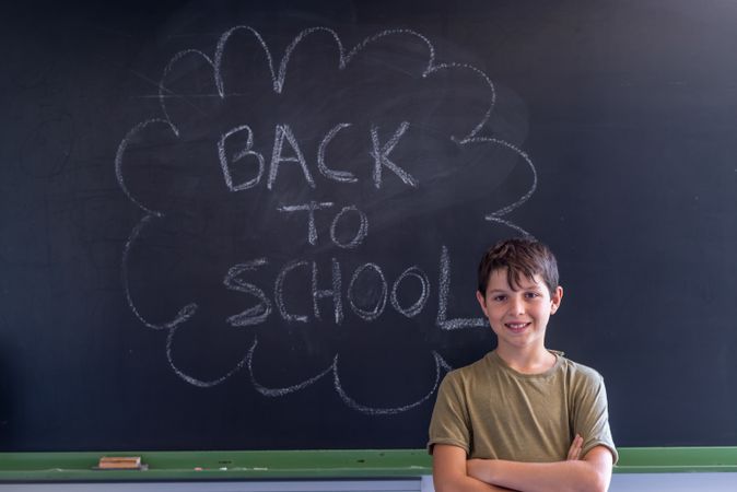 Boy standing at board with "back to school" written in chalk