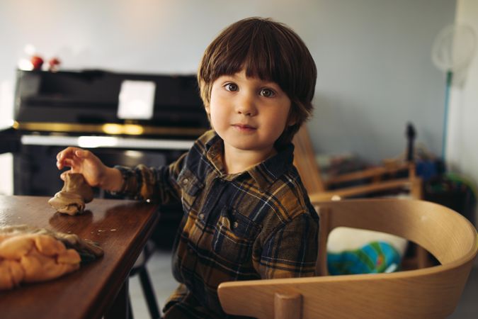 Cute boy with play clay looking at camera