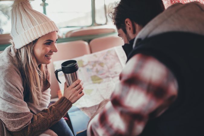 Smiling woman holding coffee and man looking at the map