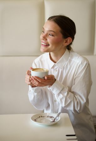 Businesswoman smiling while enjoying a coffee in a cafeteria