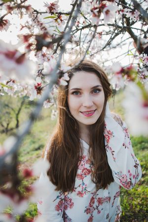 Young happy woman between trees in garden