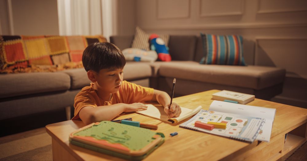 Evening Portrait of the Smart Young Boy Diligently Doing Homework in the Living Room.