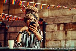 Laughing Black woman in stripe shirt taking selfie on phone in cafe 47oeA4