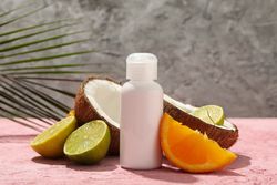 Coconut, fruits and cosmetics on pink background, close up