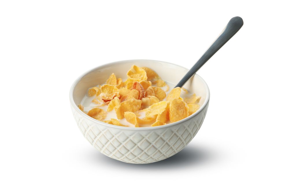 Spoon and bowl of muesli with milk isolated on plain background