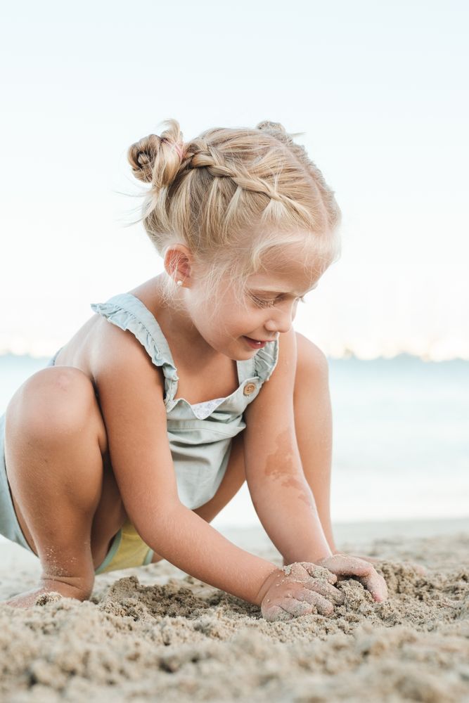 Cute girl playing with sand on beach