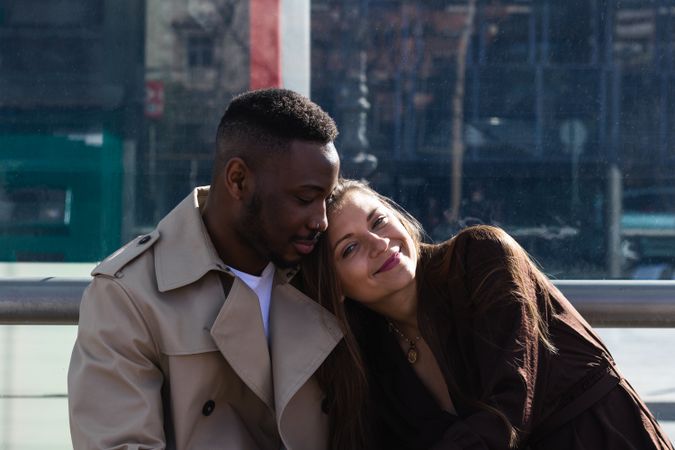 Romantic multiracial couple sitting on bus stop