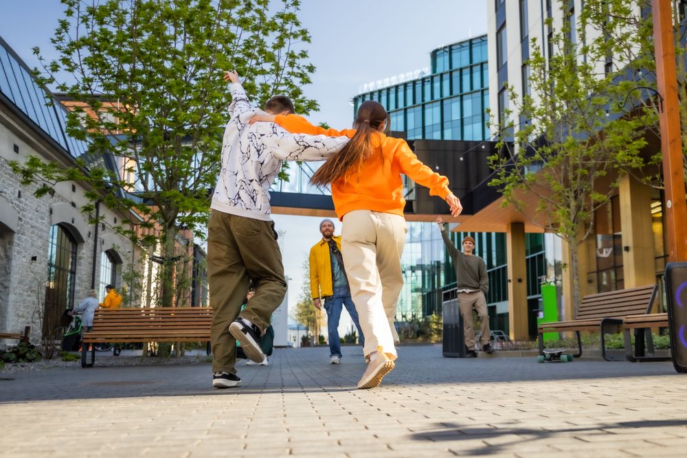 Vibrant Scene Capturing Young Adults Joyfully Dancing In A Lively Street Setting
