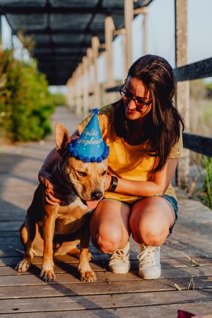 Casual young woman resting next to brown dog with party hat